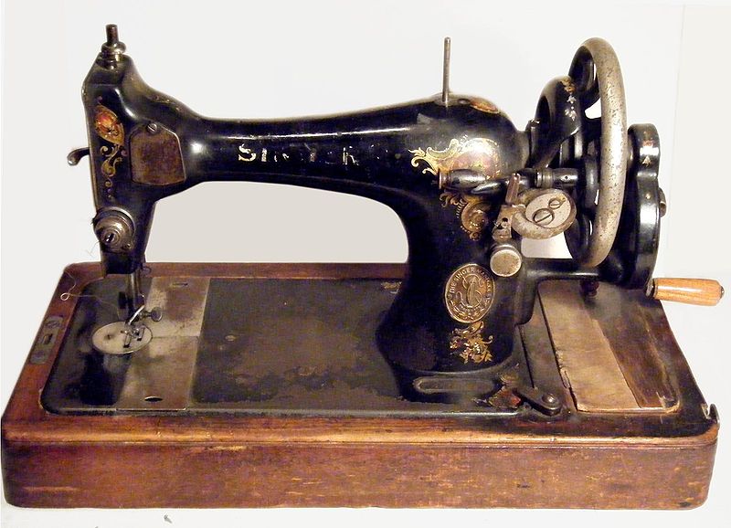 Vintage sewing machine being cleaned to remove rust using a Dremel tool and sanding sponge
