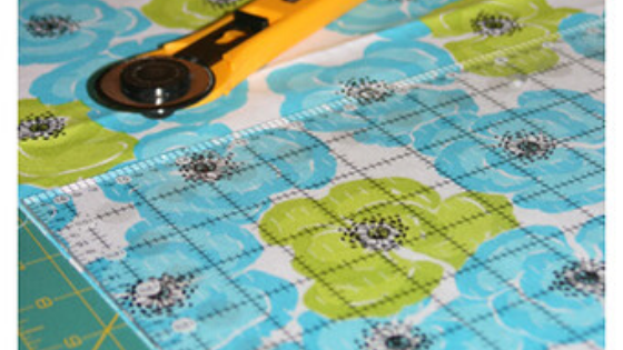 Sewing pattern pieces being cut precisely on fabric with scissors and pins