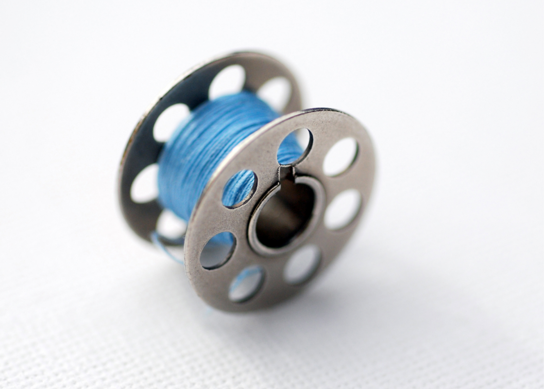 Close-up of a sewing machine bobbin being wound with thread