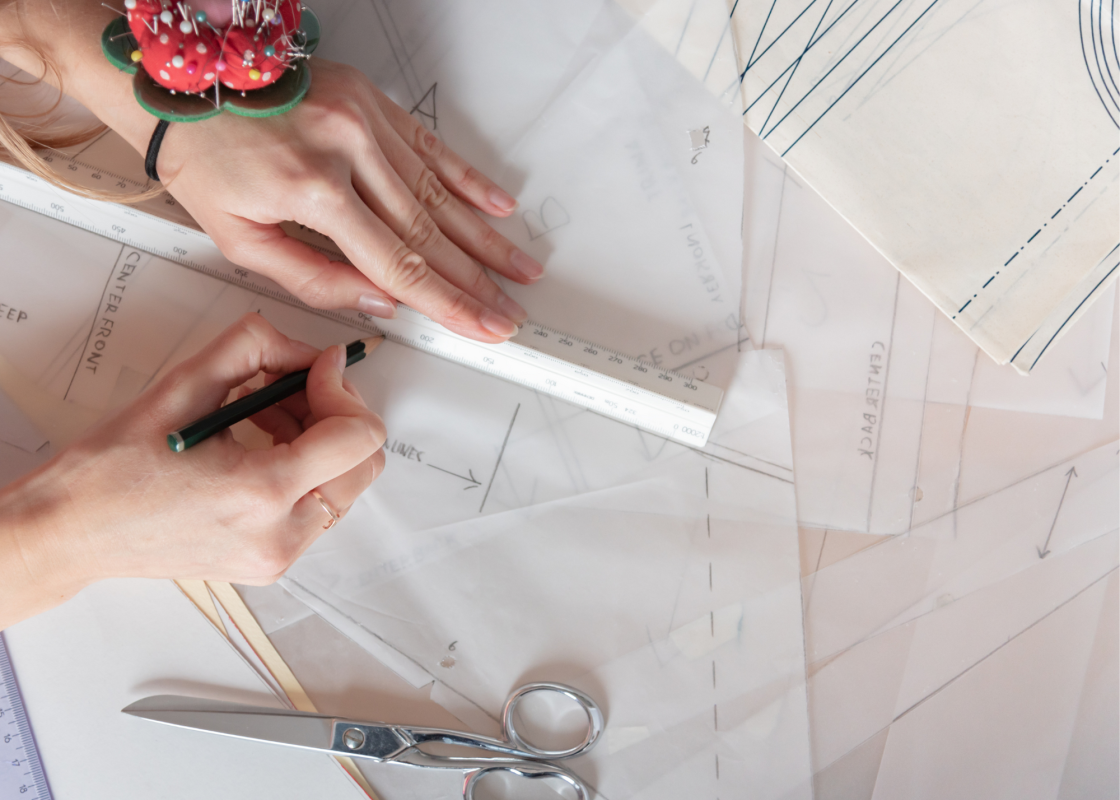 Woman reading a sewing pattern with fabric and scissors on table
